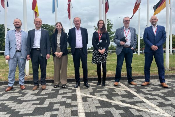 Digital Infrastructure and England's Connected Heartland team with European Space Agency (ESA) team members standing outside of the building next to the flags